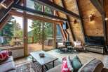 Experience breathtaking mountain views from this stunning A-frame cabin living room, featuring a cozy fireplace and expansive windows that seamlessly blend indoor and outdoor living.