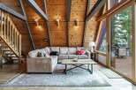 Experience rustic charm in this A-frame living room, featuring exposed wooden beams and a cozy sectional sofa perfect for gathering.