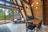 Experience rustic charm in this A-frame cabin living area, featuring a cozy fireplace and a dining set perfect for intimate gatherings.