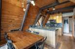 Experience rustic charm in this A-frame kitchen and dining area, featuring warm wood paneling and exposed beams.