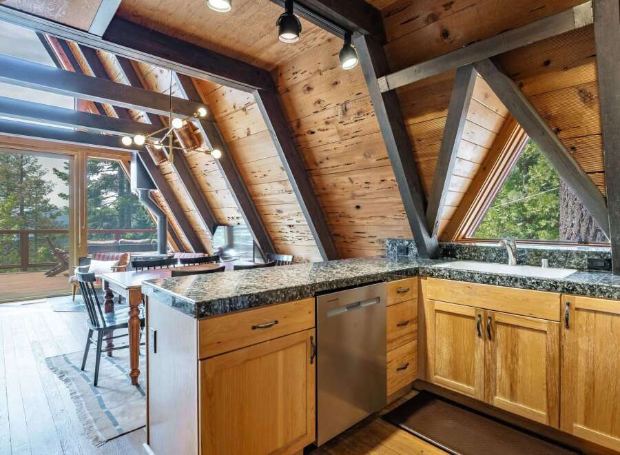 Experience rustic charm in this A-frame kitchen, featuring warm wood paneling and exposed beams that create a cozy, cabin-like atmosphere.