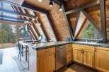 Experience rustic charm in this A-frame kitchen, featuring warm wood paneling and exposed beams that create a cozy, cabin-like atmosphere.