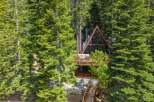 Nestled amidst lush green trees, this A-frame cabin offers a unique architectural design with expansive glass windows that bring the outdoors in.