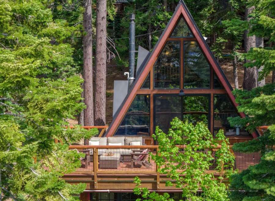 Experience the ultimate mountain retreat in this stunning A-frame cabin, nestled amidst lush greenery and towering trees.