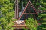 Experience the ultimate mountain retreat in this stunning A-frame cabin, nestled amidst lush greenery and towering trees.