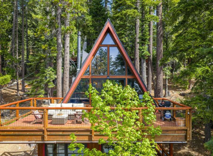 Experience modern A-frame living nestled in a serene forest setting.