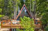 Experience modern A-frame living nestled in a serene forest setting.