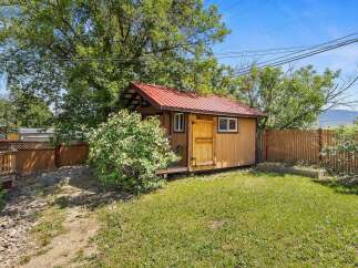 Discover this charming backyard retreat featuring a rustic wooden shed with a vibrant red metal roof, perfect for storage or a creative studio space.