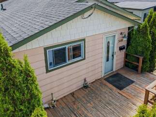 Charming single-family home featuring a welcoming front porch with a wooden deck, perfect for enjoying outdoor moments.