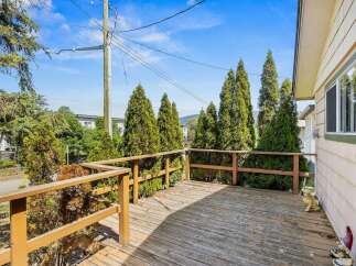 Enjoy outdoor living on this spacious wooden deck, perfect for entertaining or relaxing amidst lush greenery.