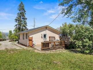 Enjoy outdoor living with this charming home featuring a spacious wooden deck, perfect for entertaining or relaxing.