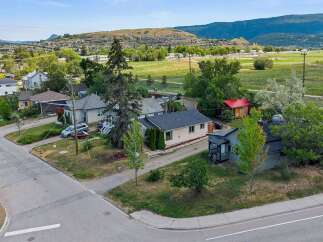 Discover this charming property featuring a cozy main house with a detached red-roofed shed, perfect for storage or a workshop.