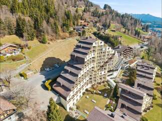 Discover this stunning tiered apartment building nestled in a picturesque mountain landscape.