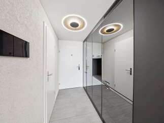 Step into a modern hallway featuring a sleek, textured wall with a black digital panel.