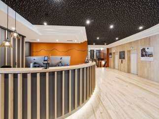 Discover a modern and inviting reception area featuring a sleek, curved reception desk with wooden accents and integrated lighting.