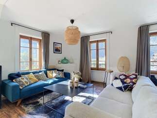 Experience cozy living in this inviting living room, featuring a plush teal sofa adorned with decorative pillows and a complementary cream sectional.