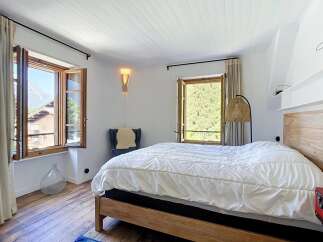 Experience serene mountain living in this charming bedroom, featuring a cozy wooden bed and large windows that frame breathtaking natural views.
