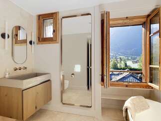 Experience luxury in this stunning bathroom featuring a sleek stone sink and warm wooden vanity.
