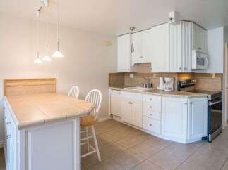 This kitchen features a spacious island with a tiled countertop, perfect for casual dining or meal preparation.