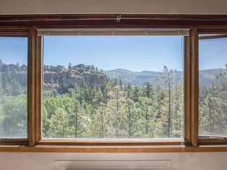 Experience breathtaking panoramic views from this stunning property, showcasing a majestic cliffside adorned with modern homes and lush evergreen forests.