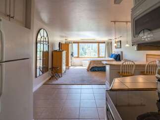 Discover this charming studio apartment featuring a comfortable bed, a well-equipped kitchenette, and a dining area with bar stools.