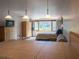 Experience comfort and convenience in this charming studio apartment, featuring a spacious bedroom area with a cozy bed and ample storage.