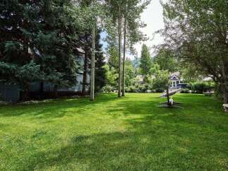 This expansive backyard offers a serene escape with lush green grass and mature trees providing ample shade.