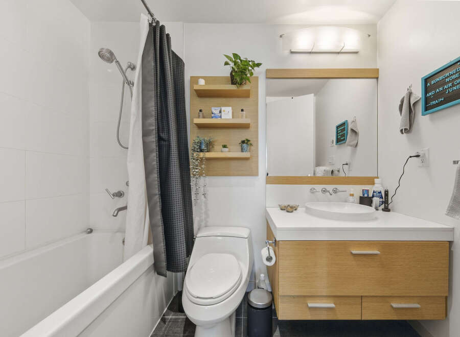 This modern bathroom features a sleek white bathtub with a chrome showerhead and a stylish dark patterned shower curtain.