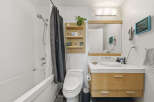 This modern bathroom features a sleek white bathtub with a chrome showerhead and a stylish dark patterned shower curtain.