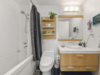 This modern bathroom features a sleek white bathtub with a chrome showerhead and a stylish dark patterned shower curtain.