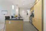 This modern kitchen boasts sleek, light wood cabinetry and a spacious island with a dark granite countertop.