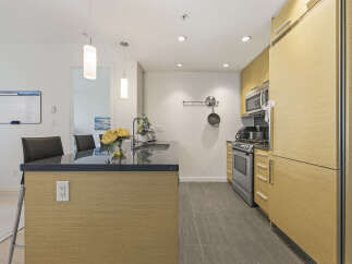 This modern kitchen boasts sleek, light wood cabinetry and a spacious island with a dark granite countertop.