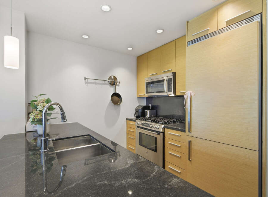 Experience modern living in this sleek kitchen featuring a spacious granite countertop island with a deep stainless steel sink and a high-arc faucet.