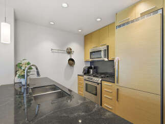 Experience modern living in this sleek kitchen featuring a spacious granite countertop island with a deep stainless steel sink and a high-arc faucet.