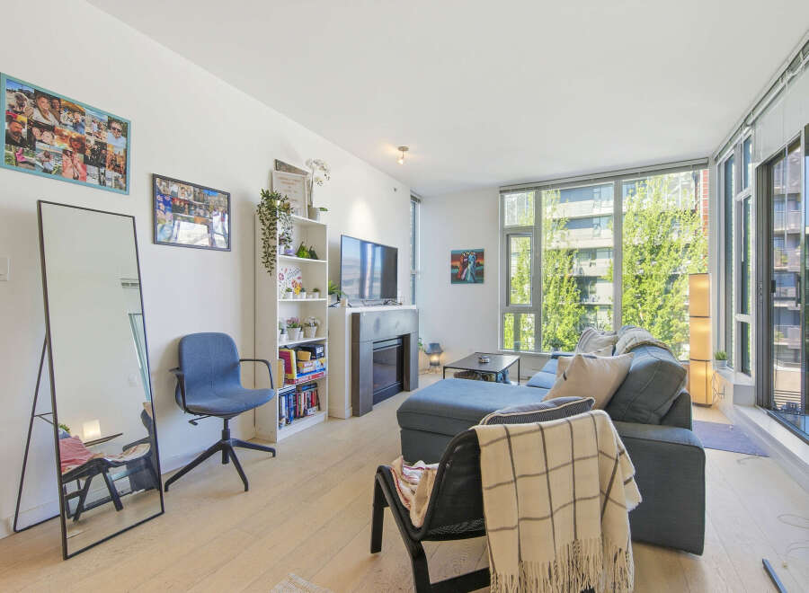 Bright and airy living room featuring a comfortable sectional sofa, a modern fireplace, and a large bookshelf filled with decor and books.