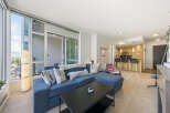 Experience modern urban living in this stunning condo featuring a spacious open-concept living area with a large sectional sofa and a sleek black coffee table.