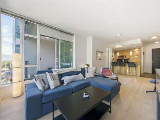 Experience modern urban living in this stunning condo featuring a spacious open-concept living area with a large sectional sofa and a sleek black coffee table.