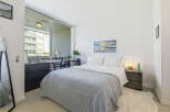Experience modern urban living in this stylish bedroom, featuring a comfortable bed adorned with a plush grey quilt.