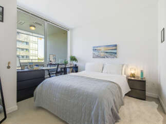 Experience modern urban living in this stylish bedroom, featuring a comfortable bed adorned with a plush grey quilt.