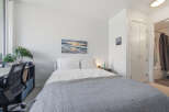 Discover comfort and style in this inviting bedroom, featuring a plush queen-size bed adorned with crisp white linens and a cozy grey quilt.