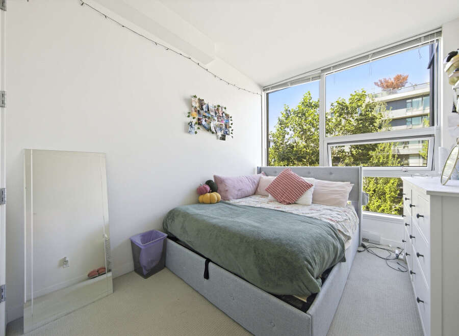 Bright and airy bedroom featuring a comfortable bed with plush pillows and a cozy green blanket.