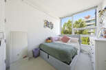Bright and airy bedroom featuring a comfortable bed with plush pillows and a cozy green blanket.