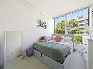 Bright and airy bedroom featuring a comfortable bed with plush pillows and a cozy green blanket.