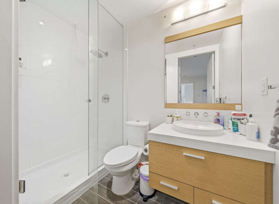 This modern bathroom features a spacious glass-enclosed shower with white tiled walls and a sleek showerhead.