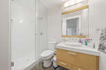 This modern bathroom features a spacious glass-enclosed shower with white tiled walls and a sleek showerhead.