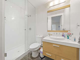 This modern bathroom features a spacious glass-enclosed shower with white tiled walls and a sleek showerhead.