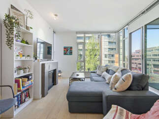 Experience modern urban living in this bright and airy condo, featuring a spacious sectional sofa perfect for relaxation and entertaining.