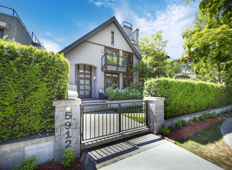 Discover this stunning modern home featuring a sleek grey stucco exterior and a welcoming arched entryway with a glass-paneled door.