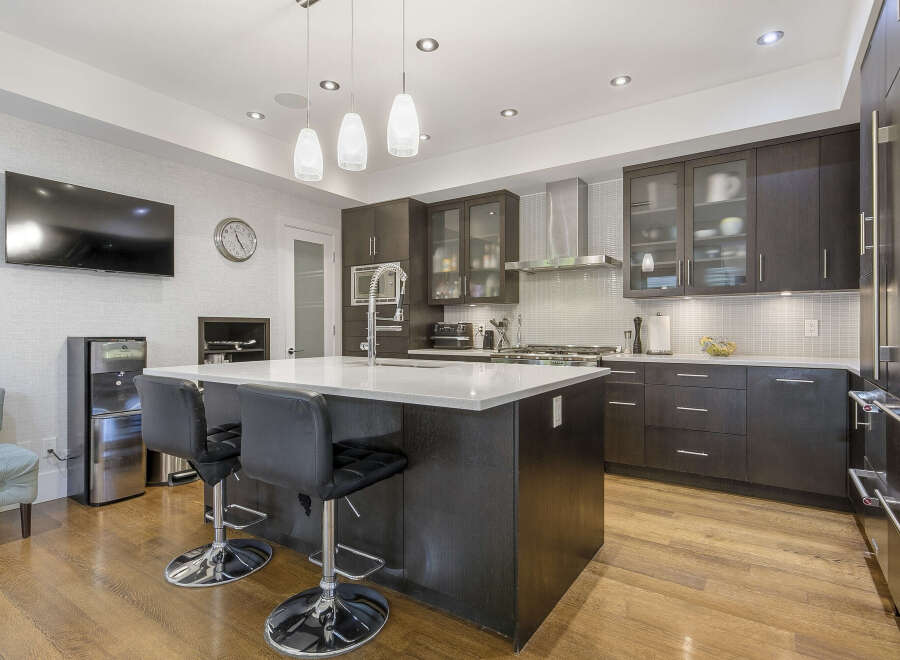 Experience modern luxury in this stunning kitchen, featuring sleek dark wood cabinetry and a spacious quartz island perfect for entertaining.