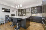 Experience modern luxury in this stunning kitchen, featuring sleek dark wood cabinetry and a spacious quartz island perfect for entertaining.
